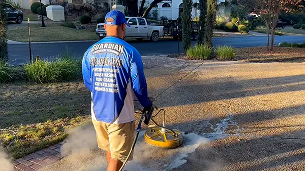A Guardian Pressure Washing employee pressure washing a driveway.